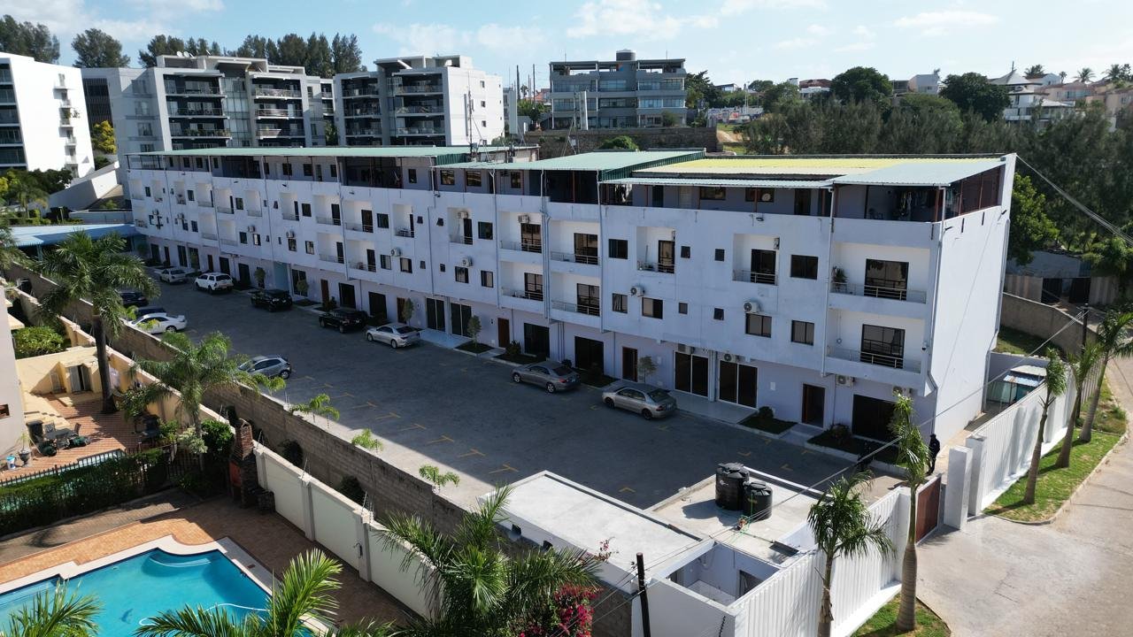 Amplo complexo de edifícios residenciais brancos com estacionamento e piscina construído na Costa do Sol em Maputo pela Esselte
